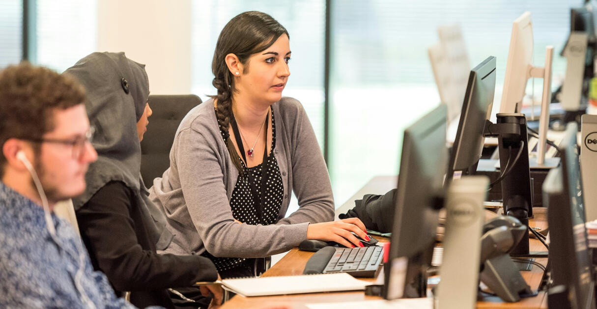Employees employees gathered around in front of computer